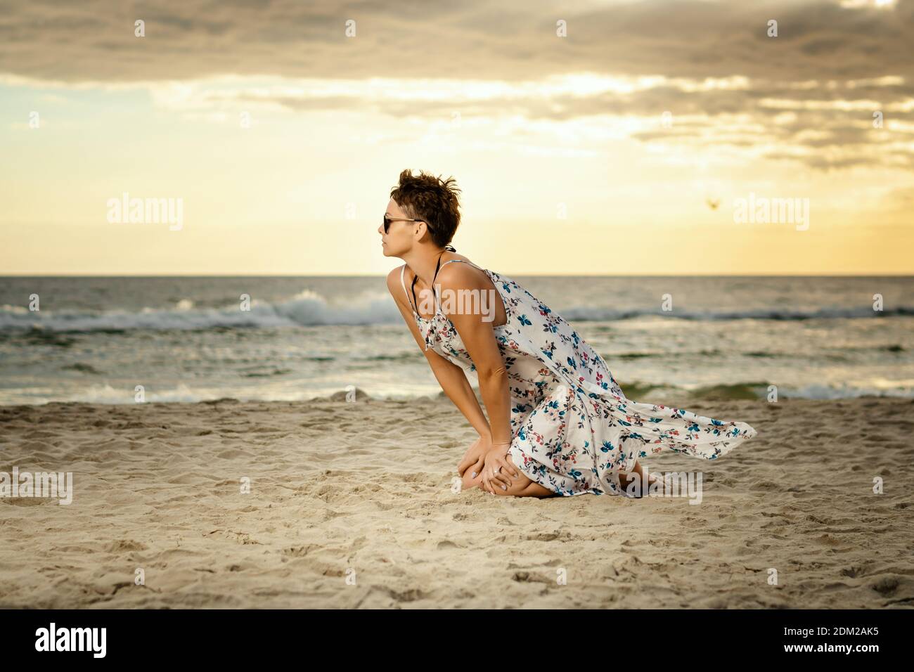 Woman kneeling sand beach sunset beach hi-res stock photography and ...