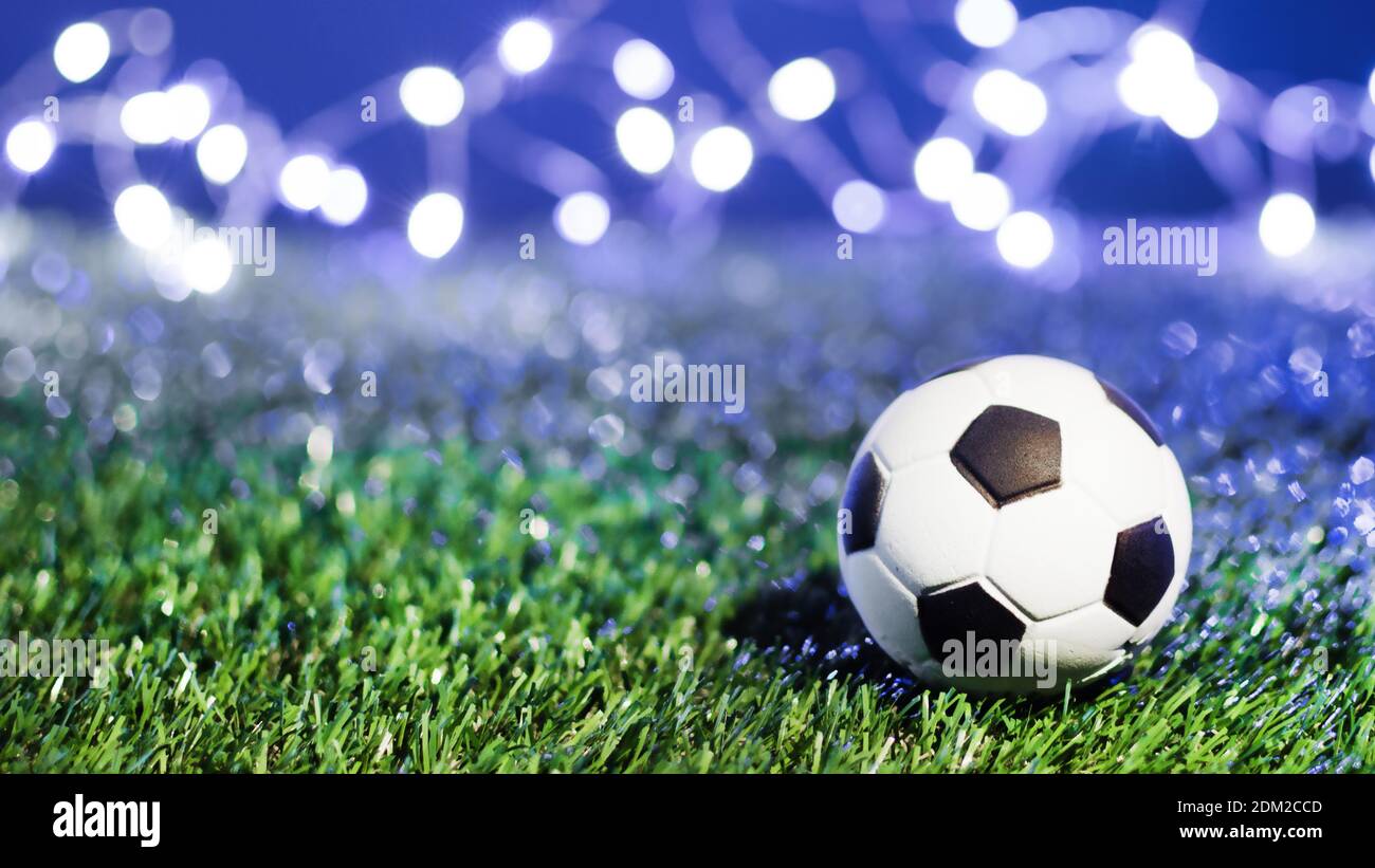 Traditional soccer ball on grass soccer field at night over winner bokeh. Football winner background. Stock Photo
