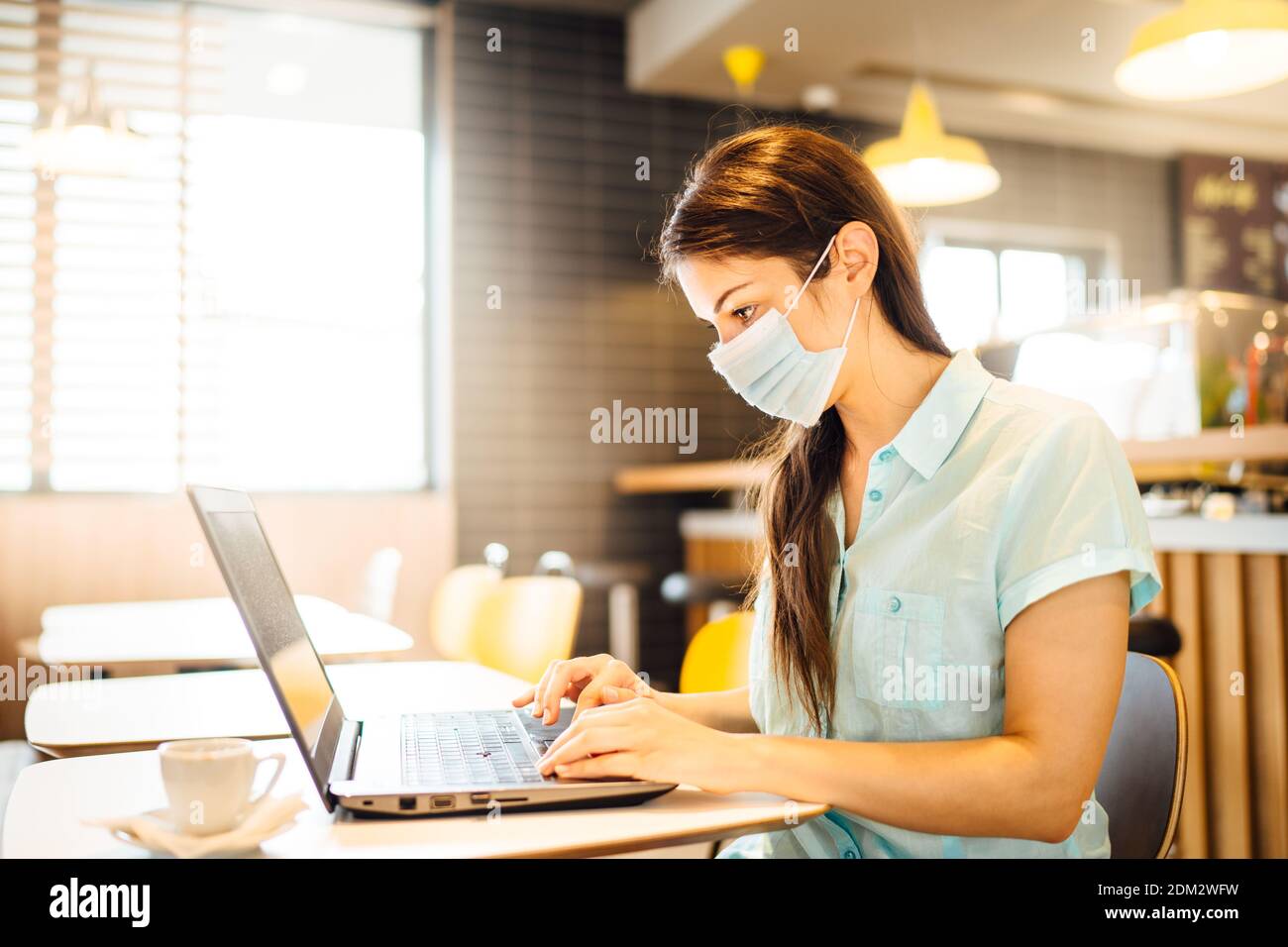 Young woman working on laptop, wearing protective face mask.Online training education and freelance work.Studying remotely.Outsourcing. Coronavirus pa Stock Photo