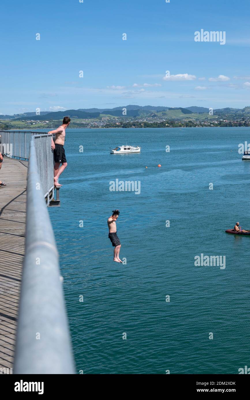 Tauranga New Zealand - December 6 2020; Jumping from historic steel truss Tauranga Railway bridge in harbour below. Stock Photo