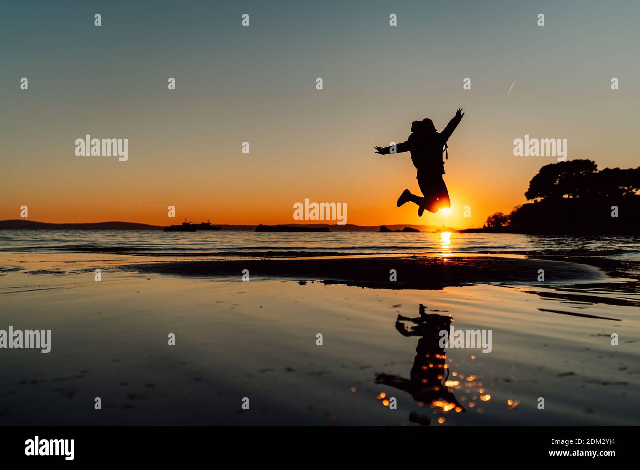 Silhouette of happy joyful woman jumping and having fun at the beach at sunset/sunrise.Freedom and happiness.Holiday vacation concept.Active woman jum Stock Photo