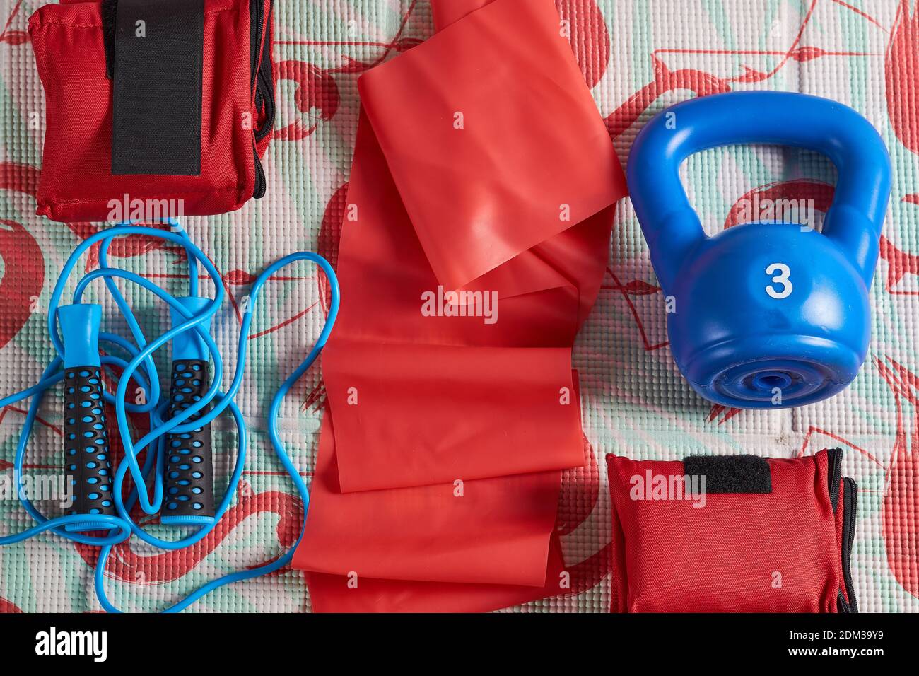 Blue jump ropes and a blue iron on a rubber sport mat with flamingos
