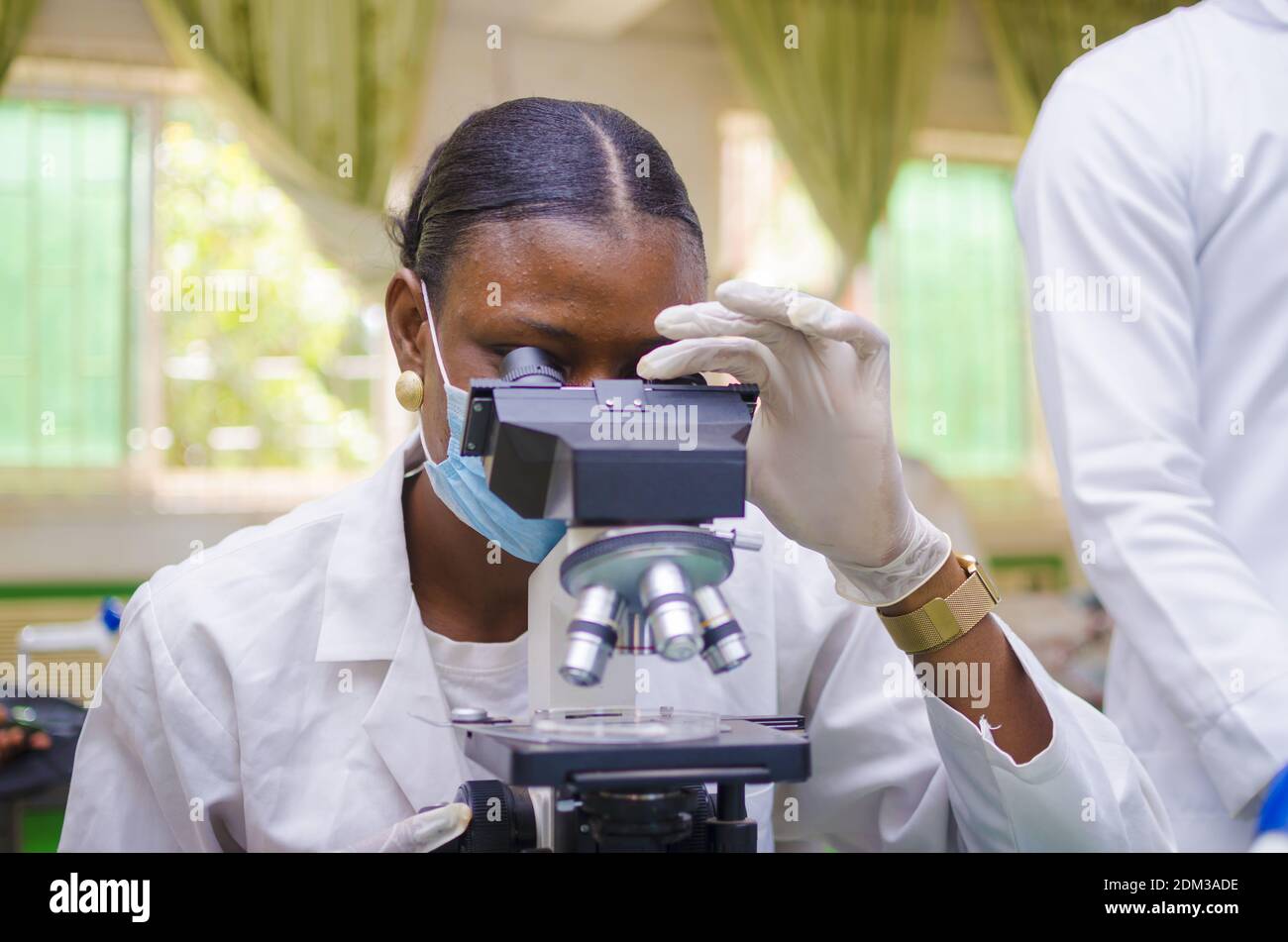 A young African scientist looking through a microscope in the ...