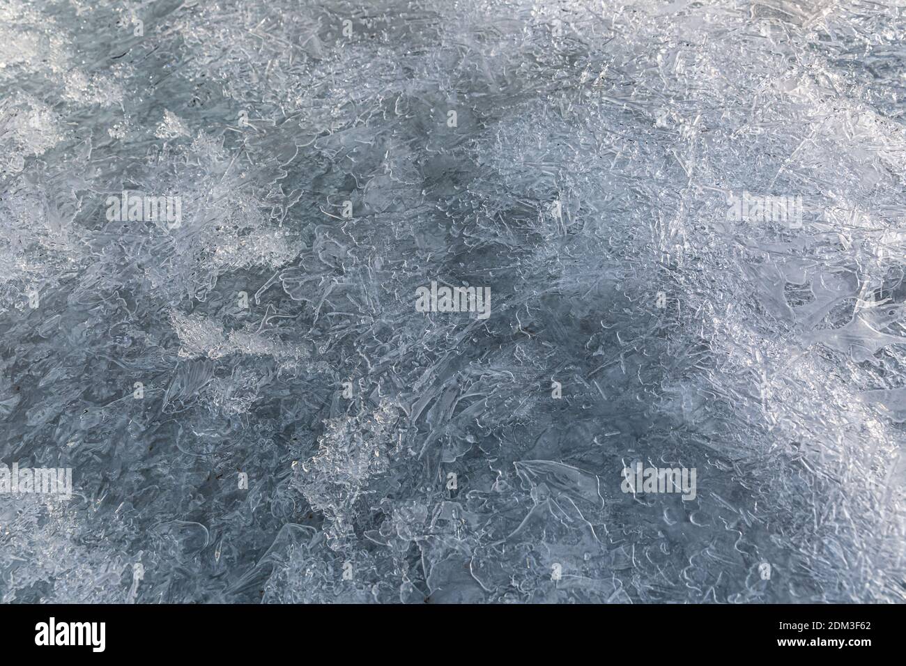 close-up of a frozen water surface in winter. Frozen ice texture. Ice background for christmas. Frozen river taken in Switzerland. Stock Photo