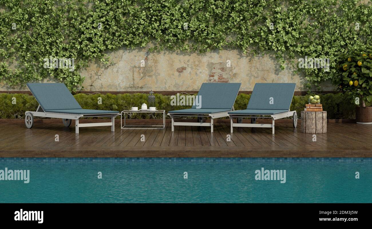 deck chairs by the pool on a wooden floor and an old wall with climbing plants - 3d rendering Stock Photo