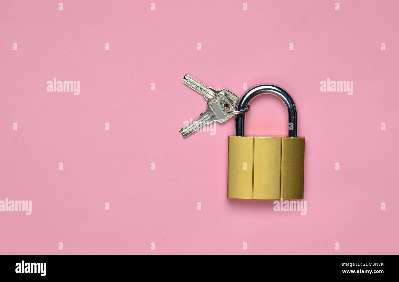 Golden closed lock with keys on a pink background. Copy space. Top View Stock Photo