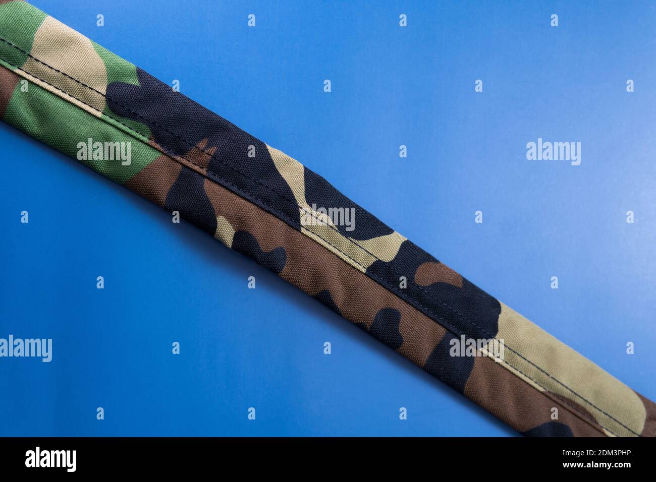 A closeup shot of a camouflage military strap on a blue background Stock Photo