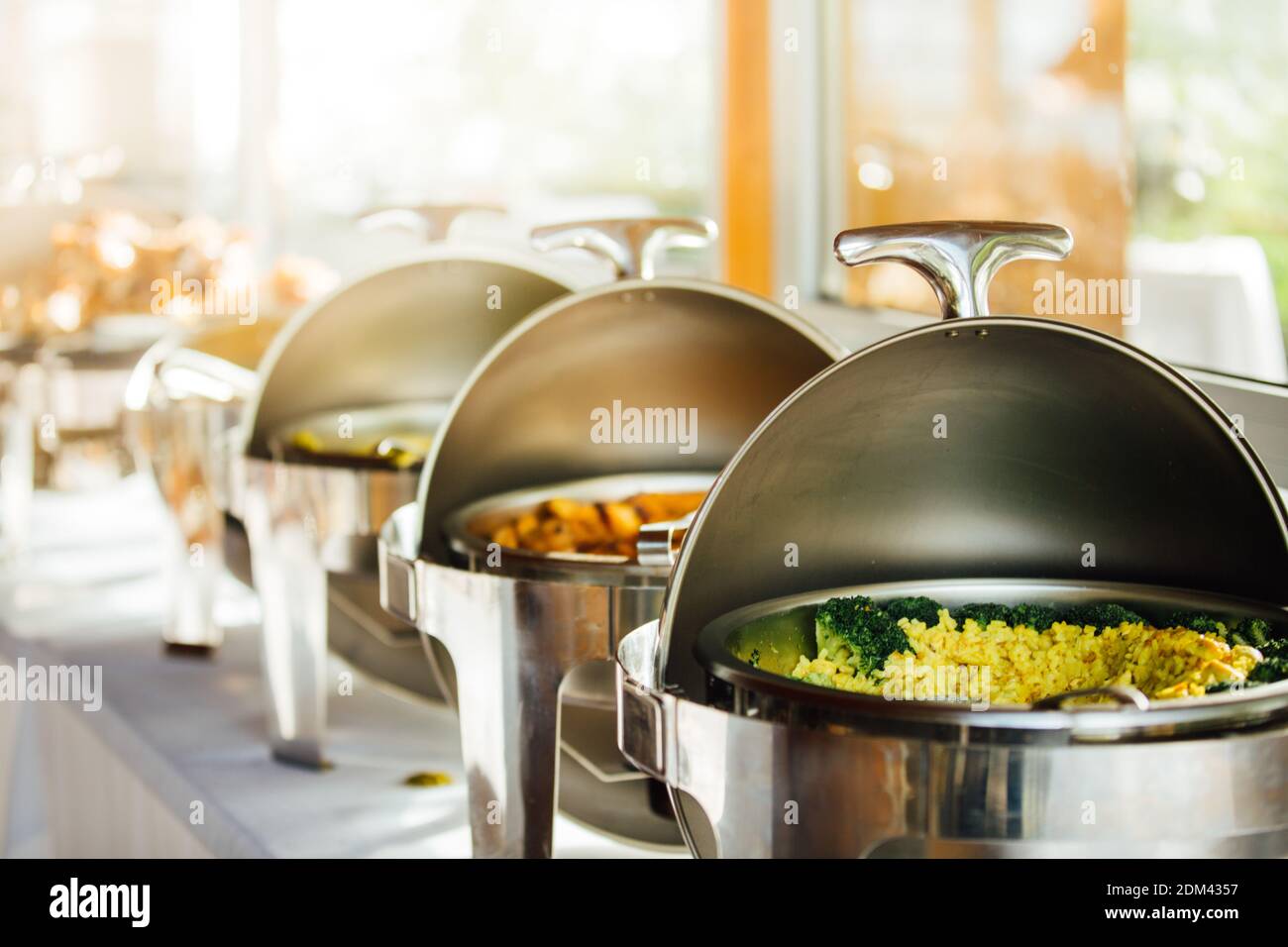 Elegant chafing dishes and food warmers with various meals served for catering reception in hotel or restaurant. Buffet served by the catering service Stock Photo