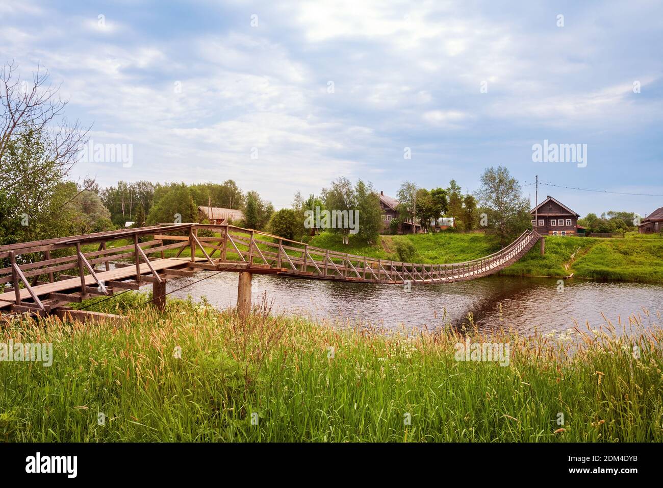 Wooden suspension pedestrian bridge in the village across the Olonka river, Karelia, Russia Stock Photo