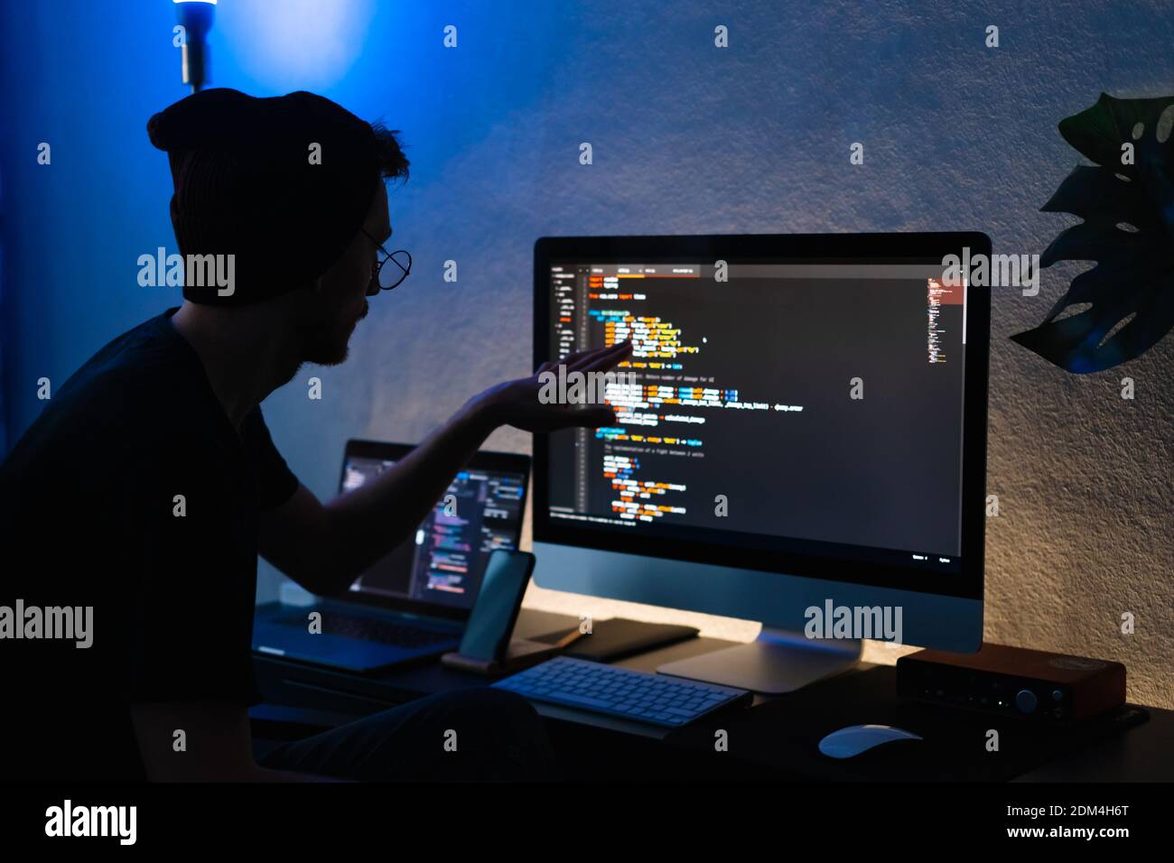 Young man mobile developer writes program code on a computer, programmer work in home office. High quality photo Stock Photo