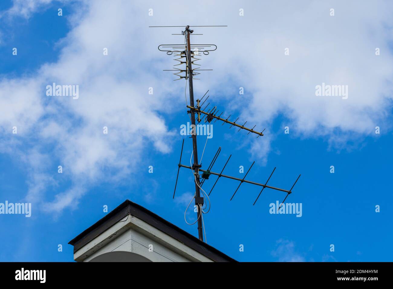 Close up view of retro antenna on blue sky with white house background