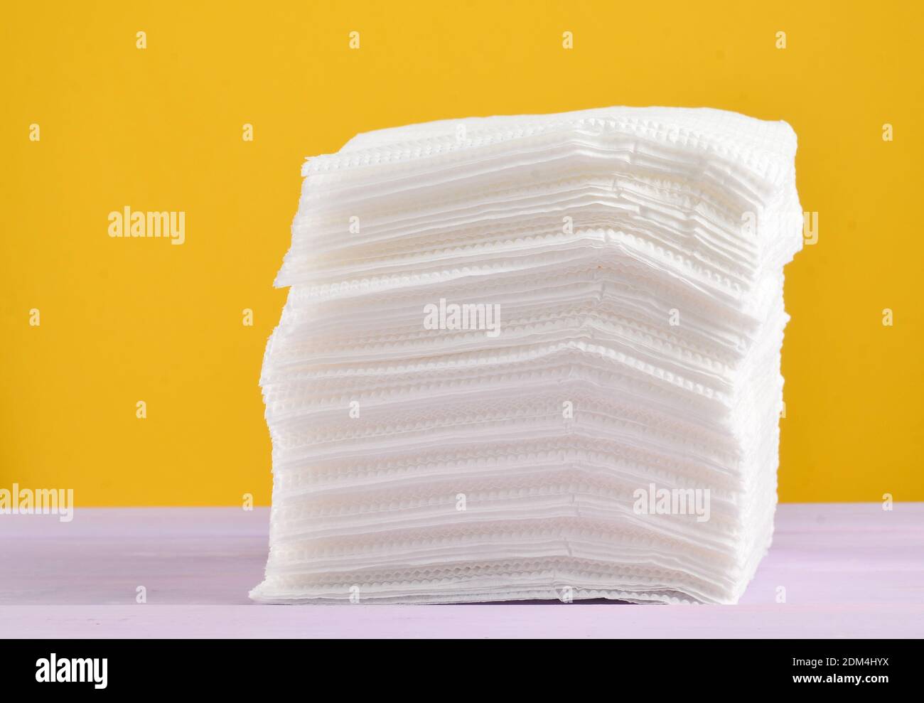 A stack of white paper napkins on a yellow pastel background Stock