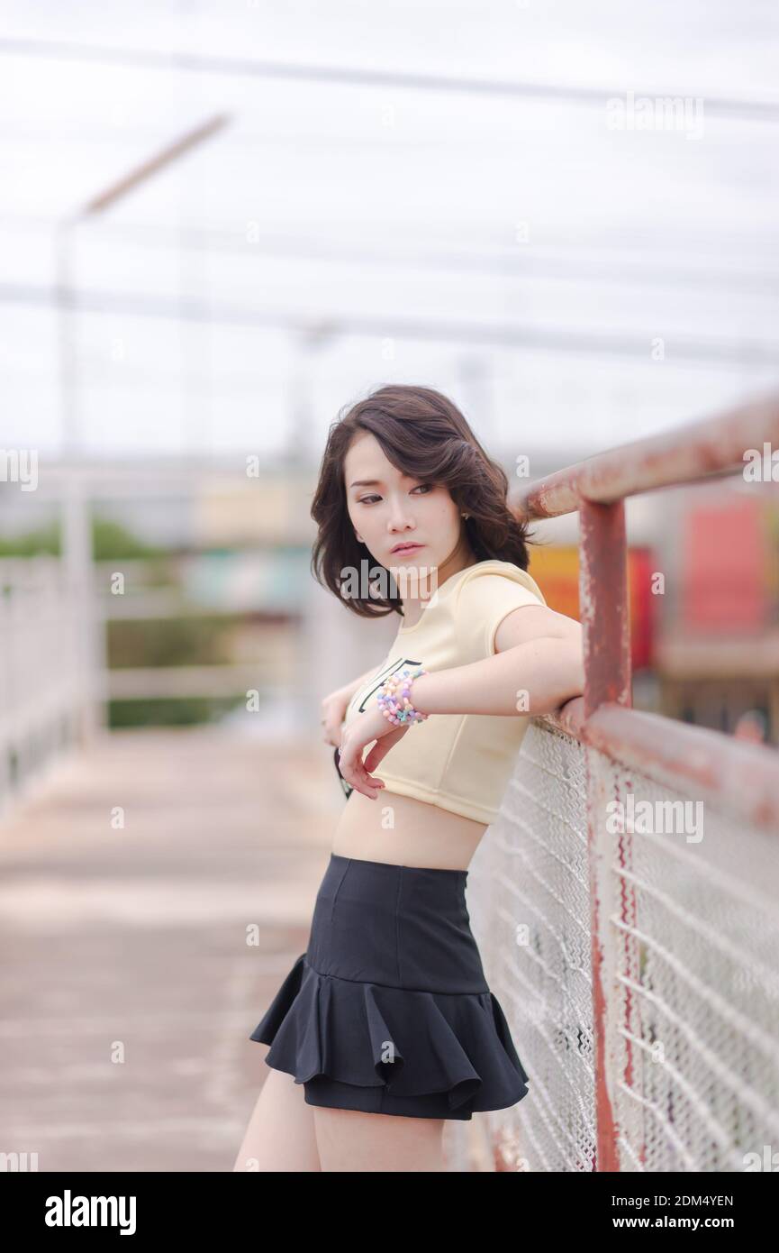 Thoughtful Young Woman Standing By Railing On Footbridge Against Sky Stock Photo