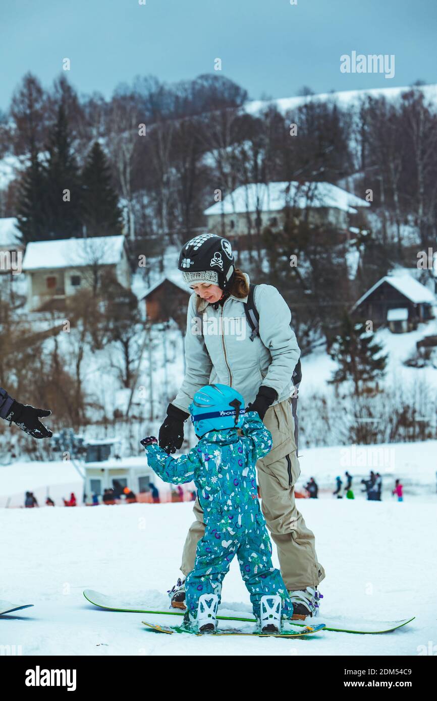 mother teaching little girl to snowboarding. lifestyle. winter