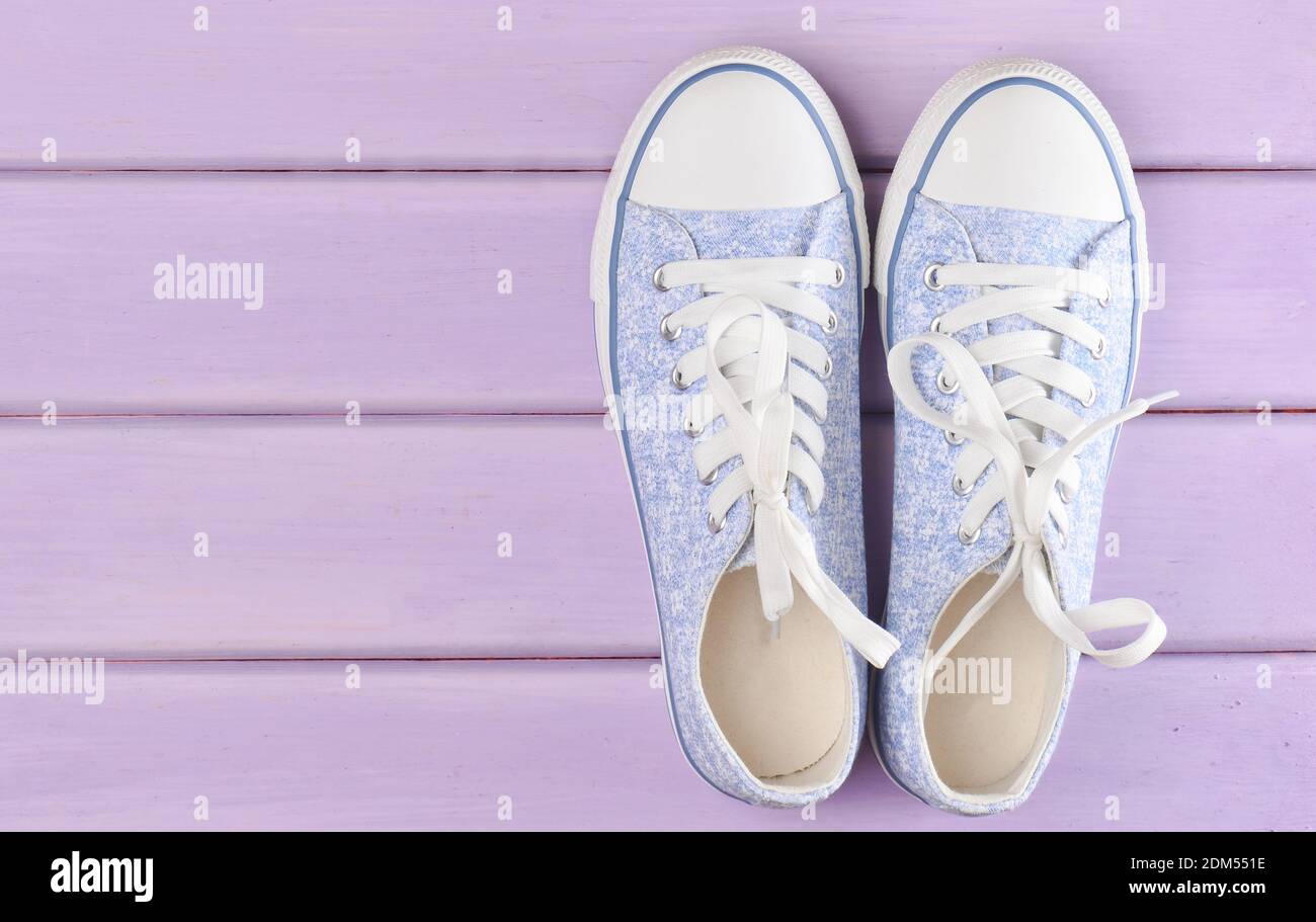 Female hipster sneakers with white laces on a pastel violet wooden ...