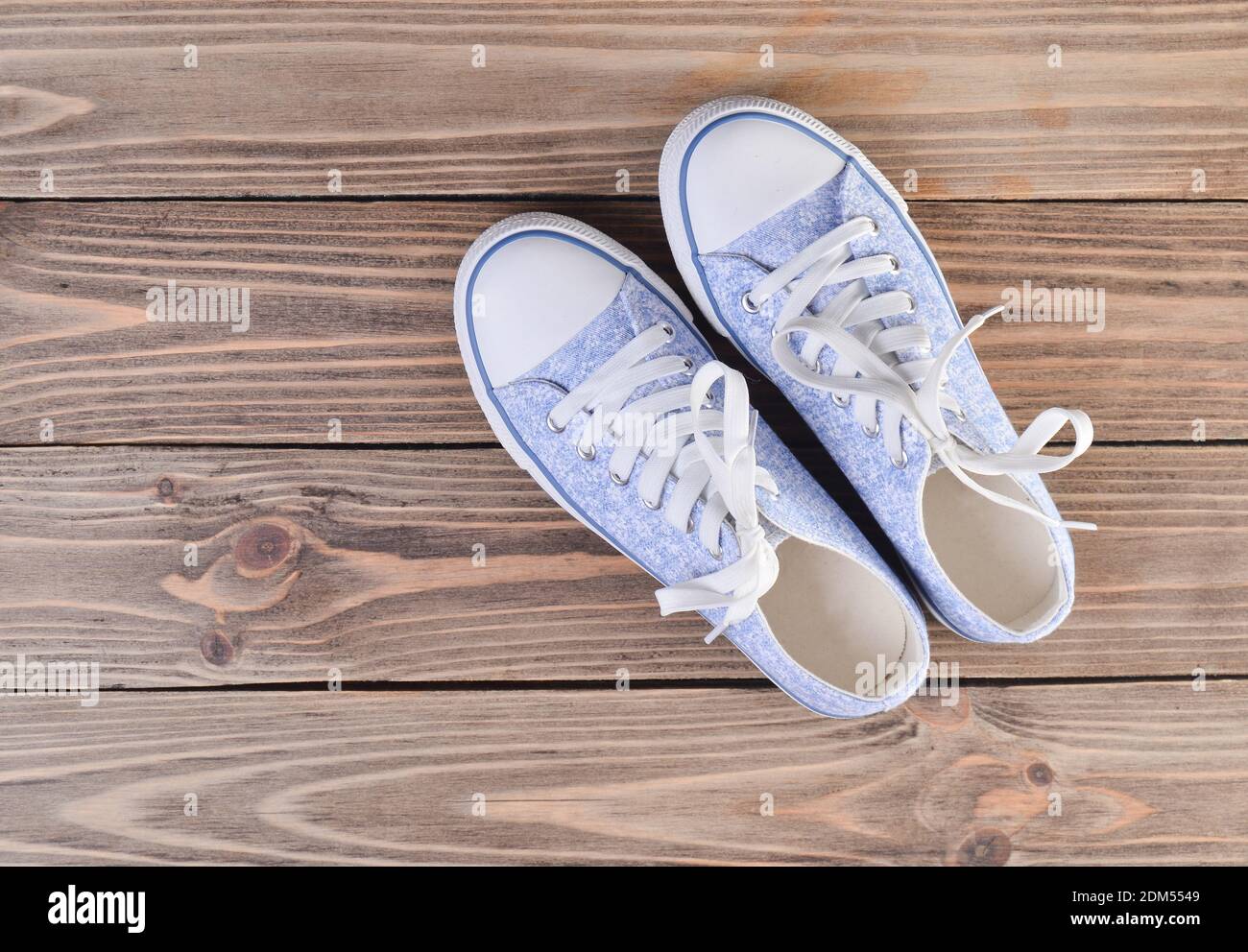 Female hipster sneakers with white laces on a pastel wooden floor, top ...