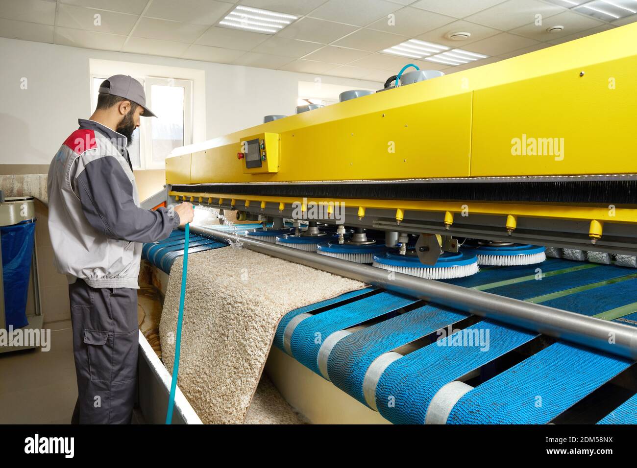 Man operating carpet automatic washing machine in professional laundry service Stock Photo