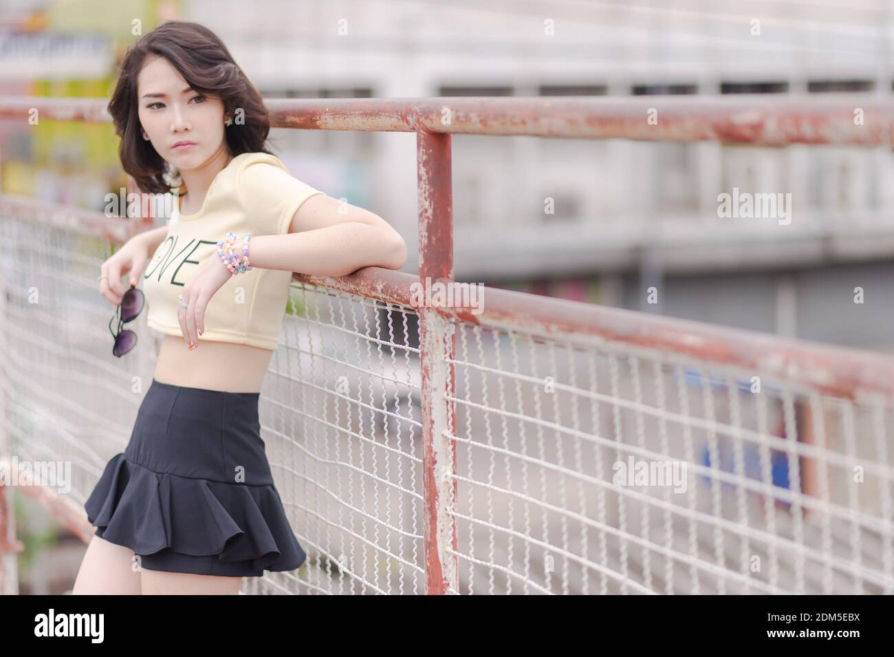 Thoughtful Young Woman Standing By Railing On Footbridge Stock Photo