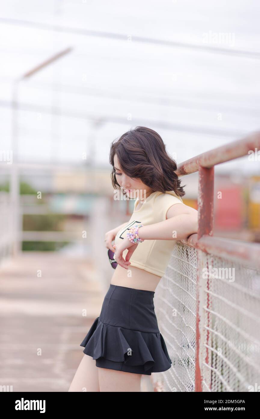 Thoughtful Young Woman Standing By Railing On Footbridge Against Sky Stock Photo