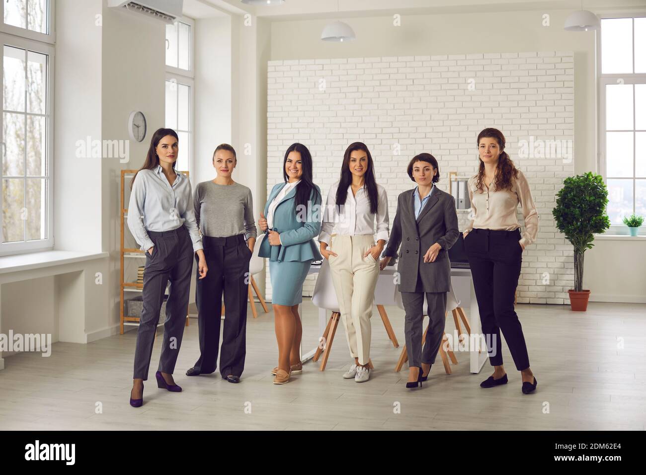 Group of confident young women standing in the company office and looking at camera Stock Photo