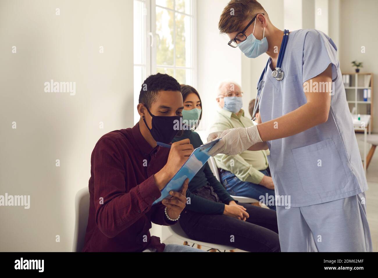 African-American man signs papers that doctor gives him before getting vaccine at the hospital Stock Photo