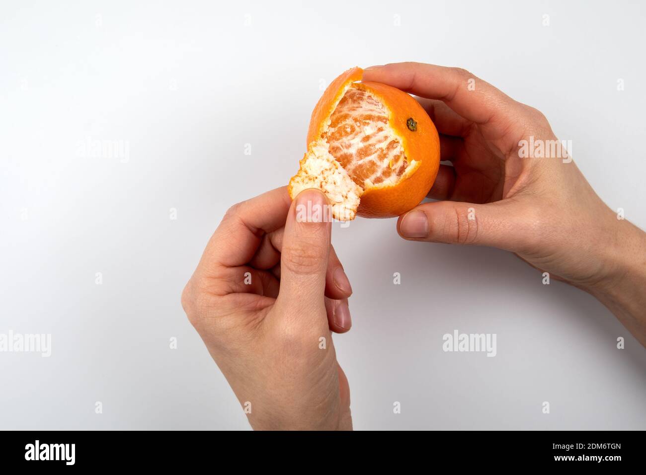 Woman peeling a tangerine. Hands on a white background. Vitamin c ...