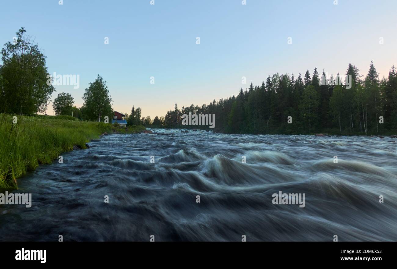 Kengis rapids on Torne river in Northern Sweden near border with Finland with midnight sun in early morning. Stock Photo