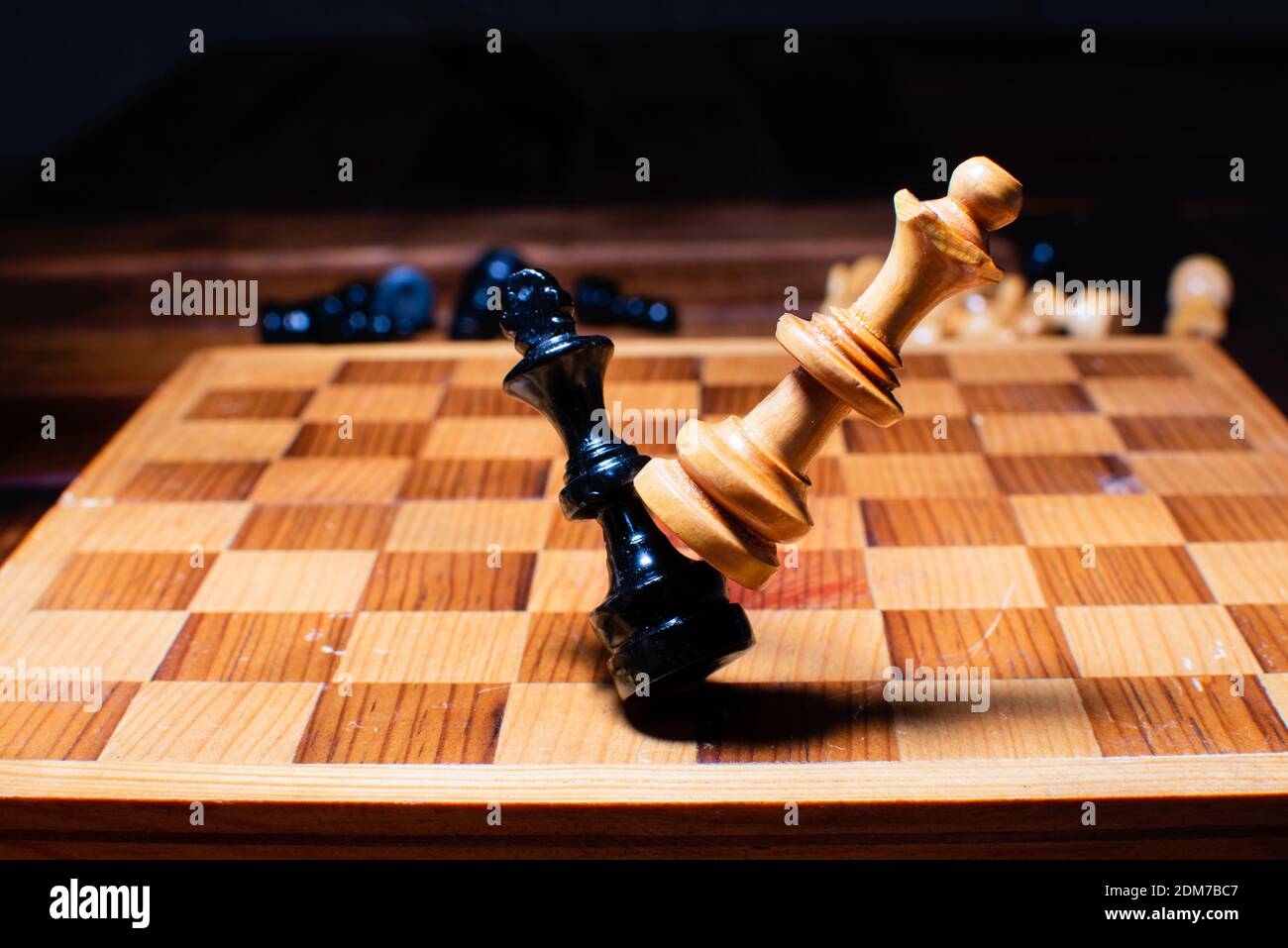 A Wooden chess pieces, the queen knocking down the king Stock Photo - Alamy