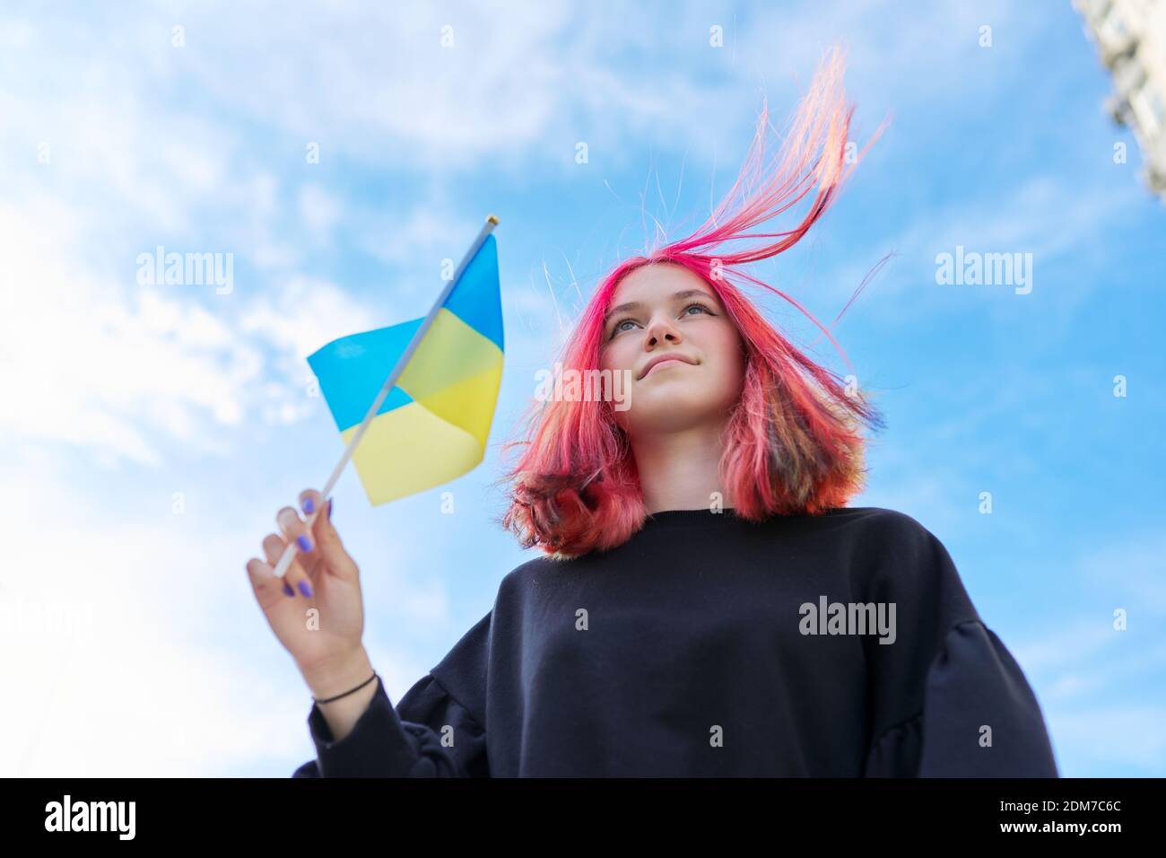 Female student teenager with Ukraine flag, blue sky with clouds background Stock Photo