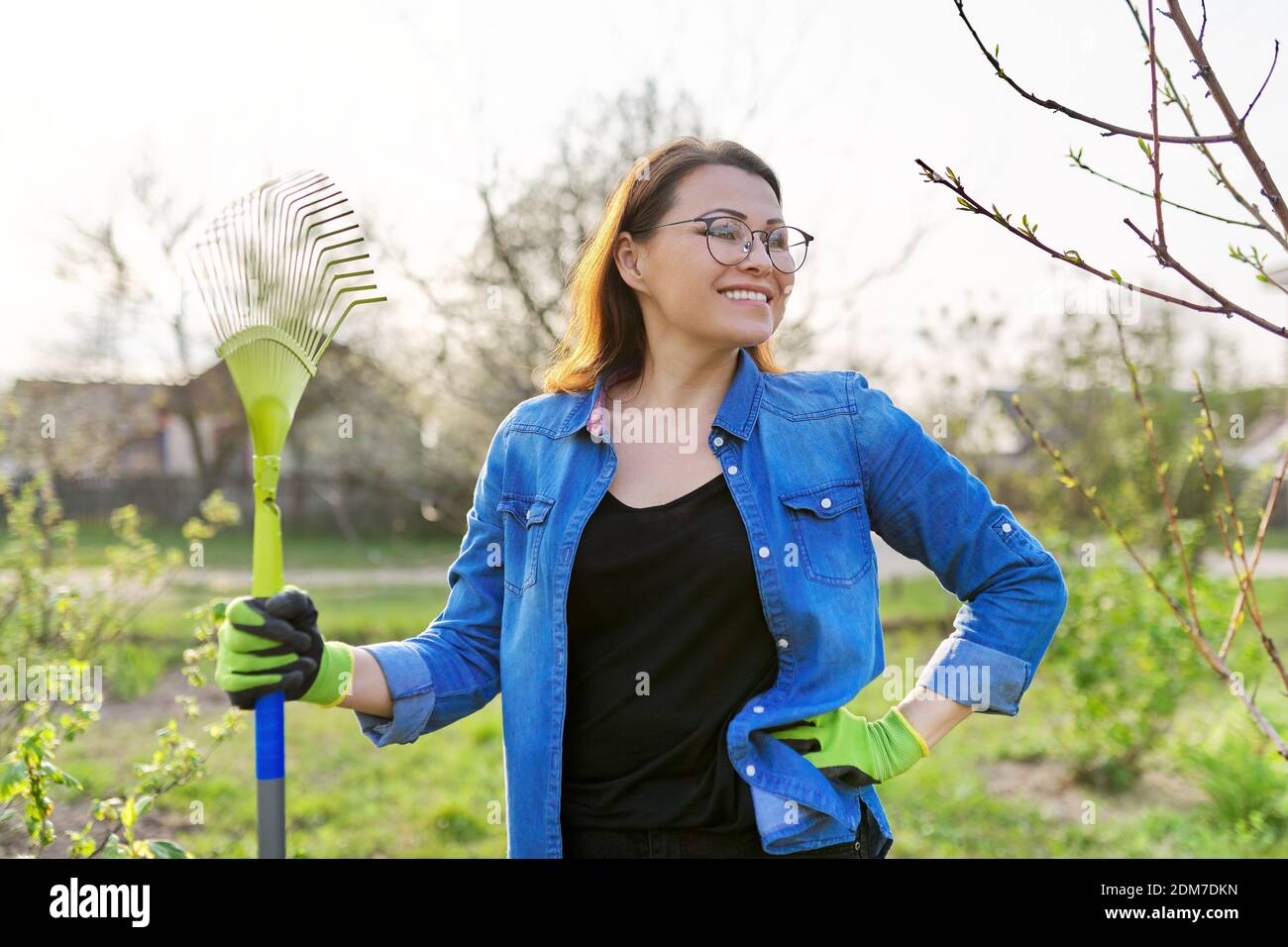 Spring gardening, portrait of mature smiling woman gardener with rake ...