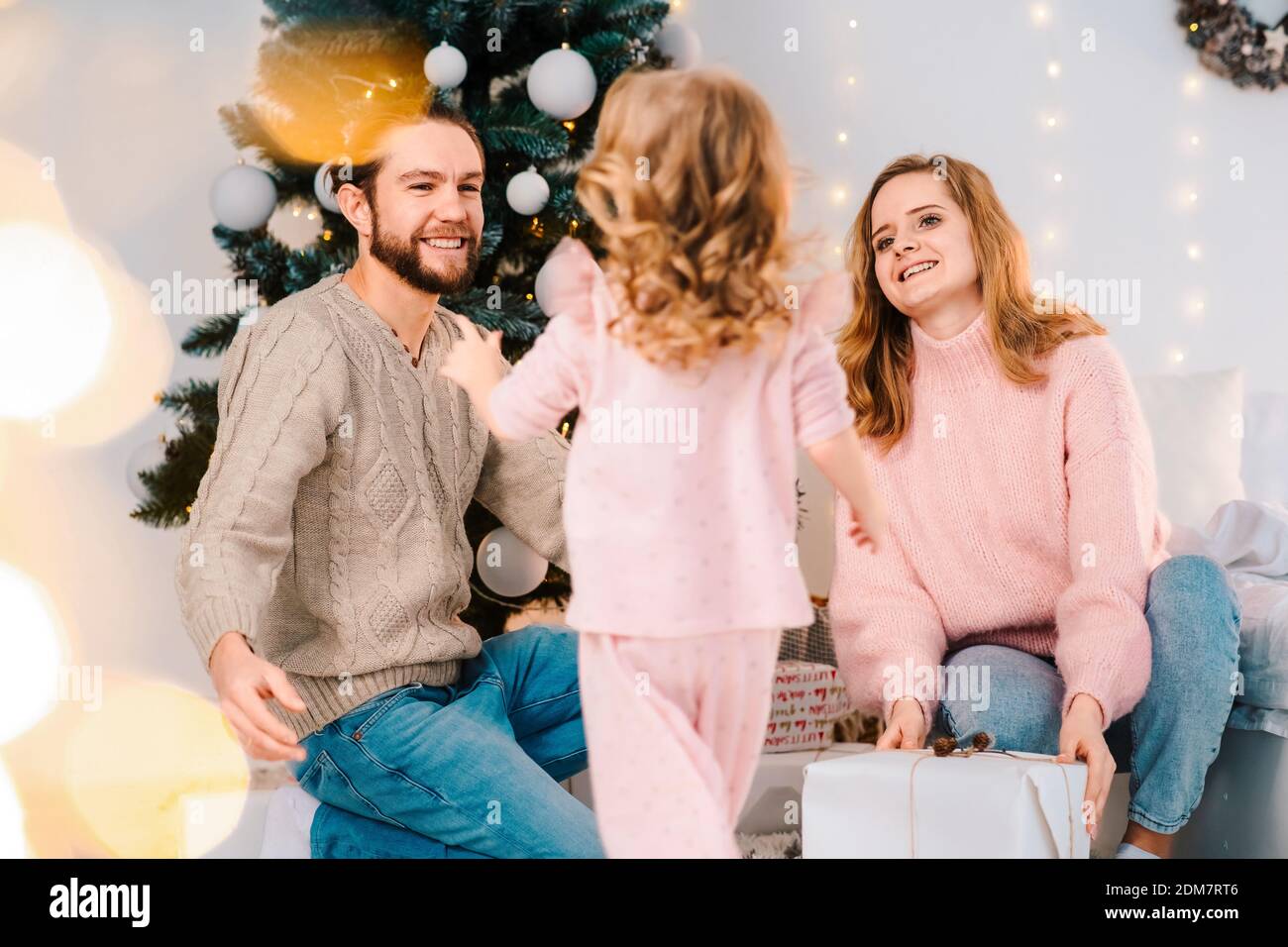 Happy family gives their daughter Christmas gifts. Little girl rejoices