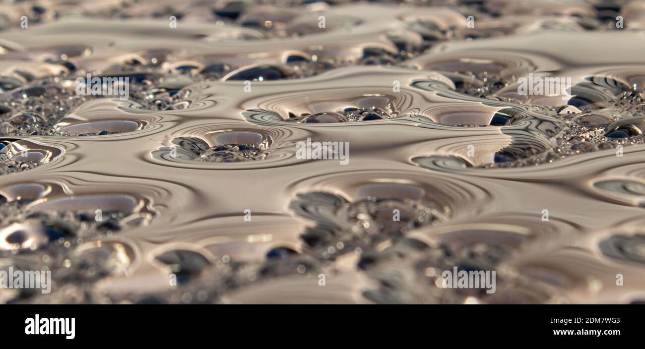 Abstract / desktop wallpaper background of a macro shot of water on a  garden table outside which looks like molten metal with unusual textures  Stock Photo - Alamy