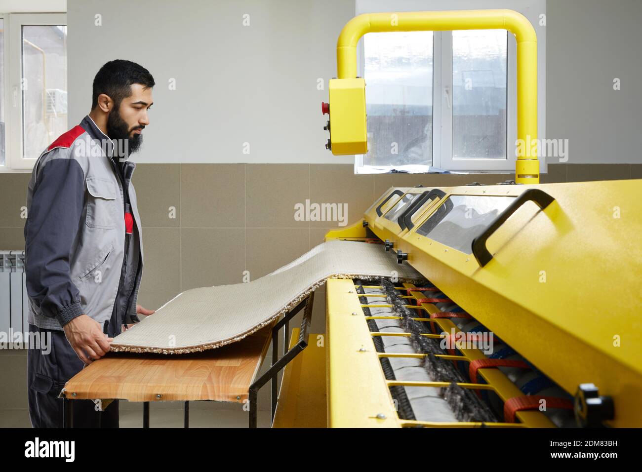 Man operating carpet automatic washing machine in professional laundry service Stock Photo