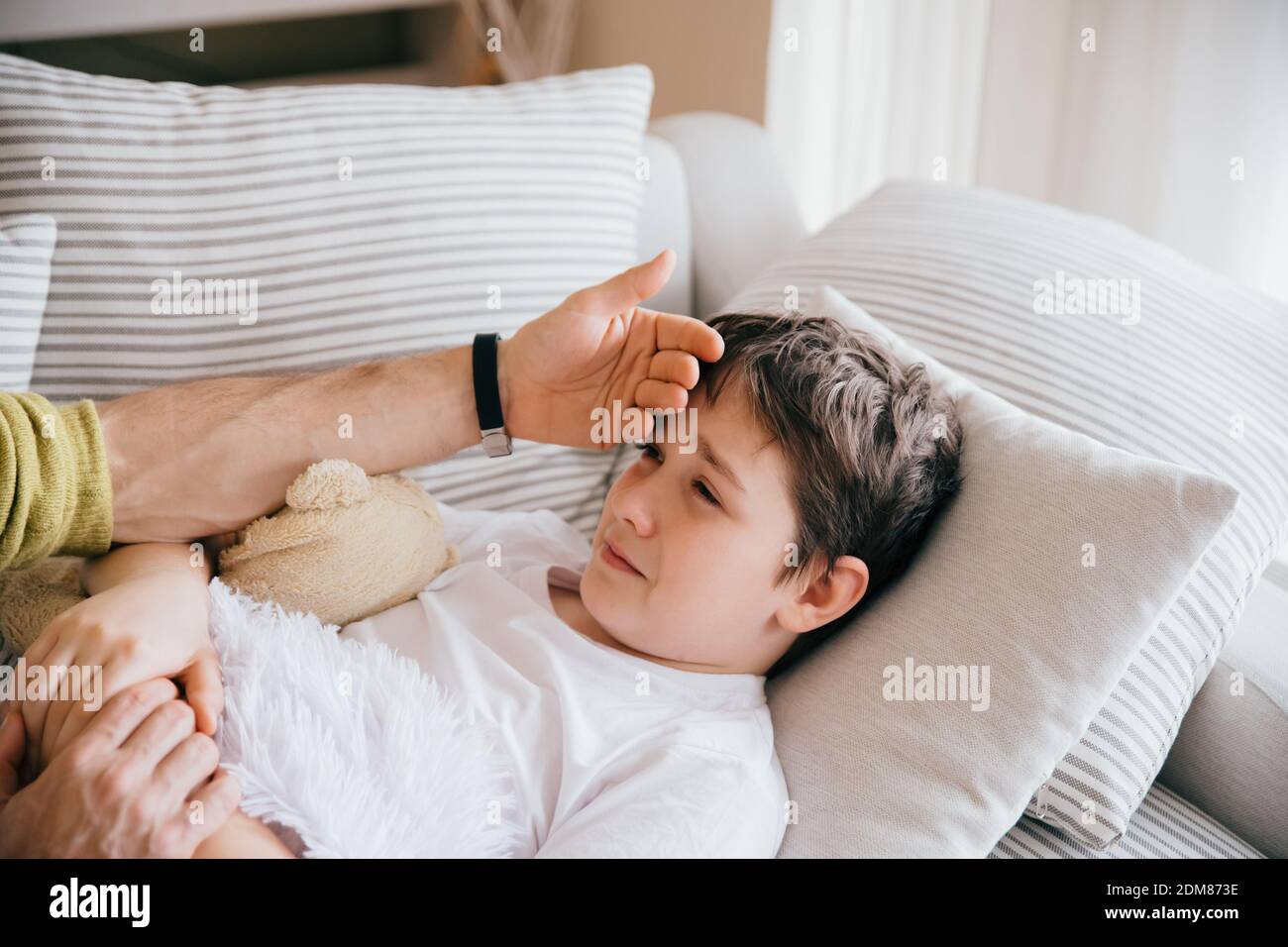 Father caring for sick son lying. Stock Photo