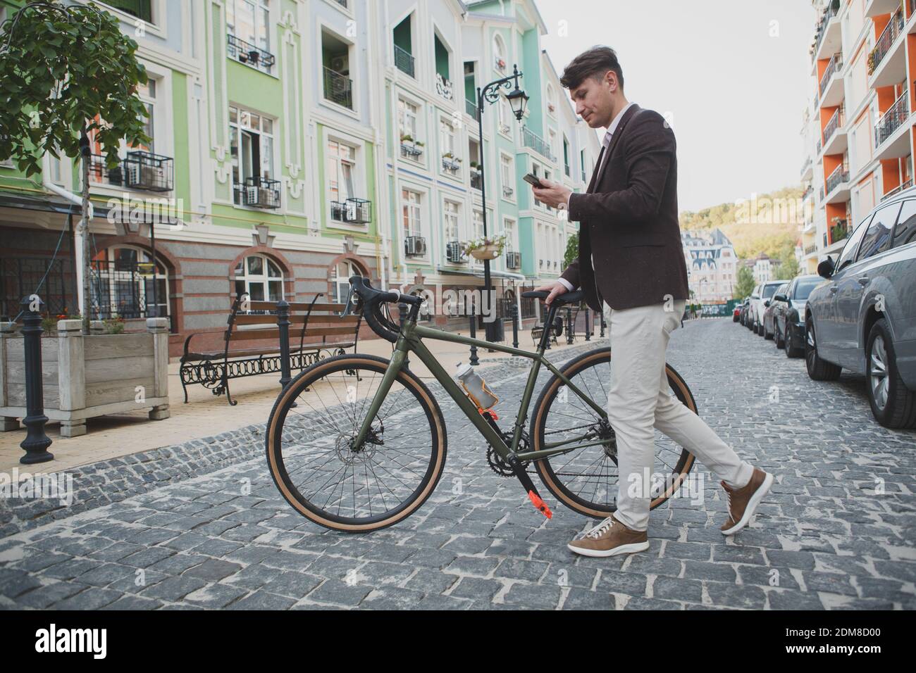 Full length shot of a stylish hipster mature man crossing the street with his bike, using smart phone Stock Photo
