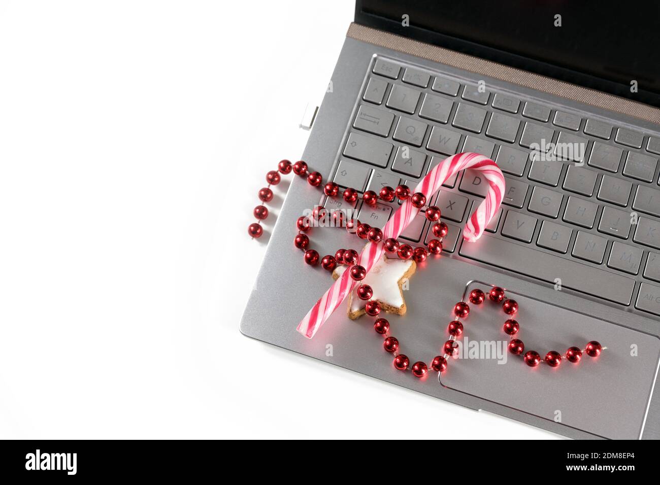 Christmas decoration and sweets on a laptop, holiday online shopping during the coronavirus  pandemic, white background with copy space, high angle vi Stock Photo