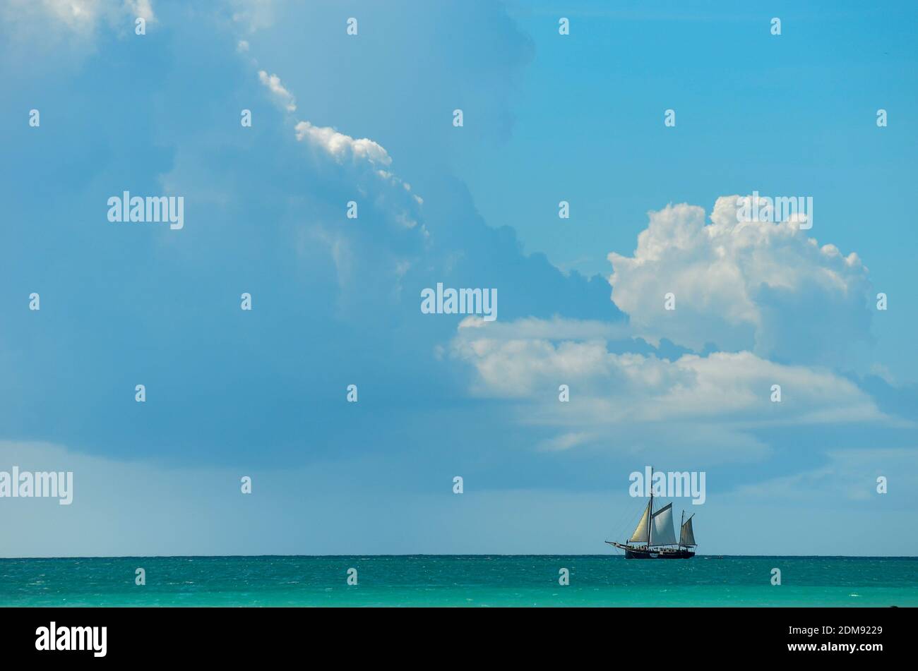 An old style ship with big sails at the horizon under a cloudy sky Stock Photo