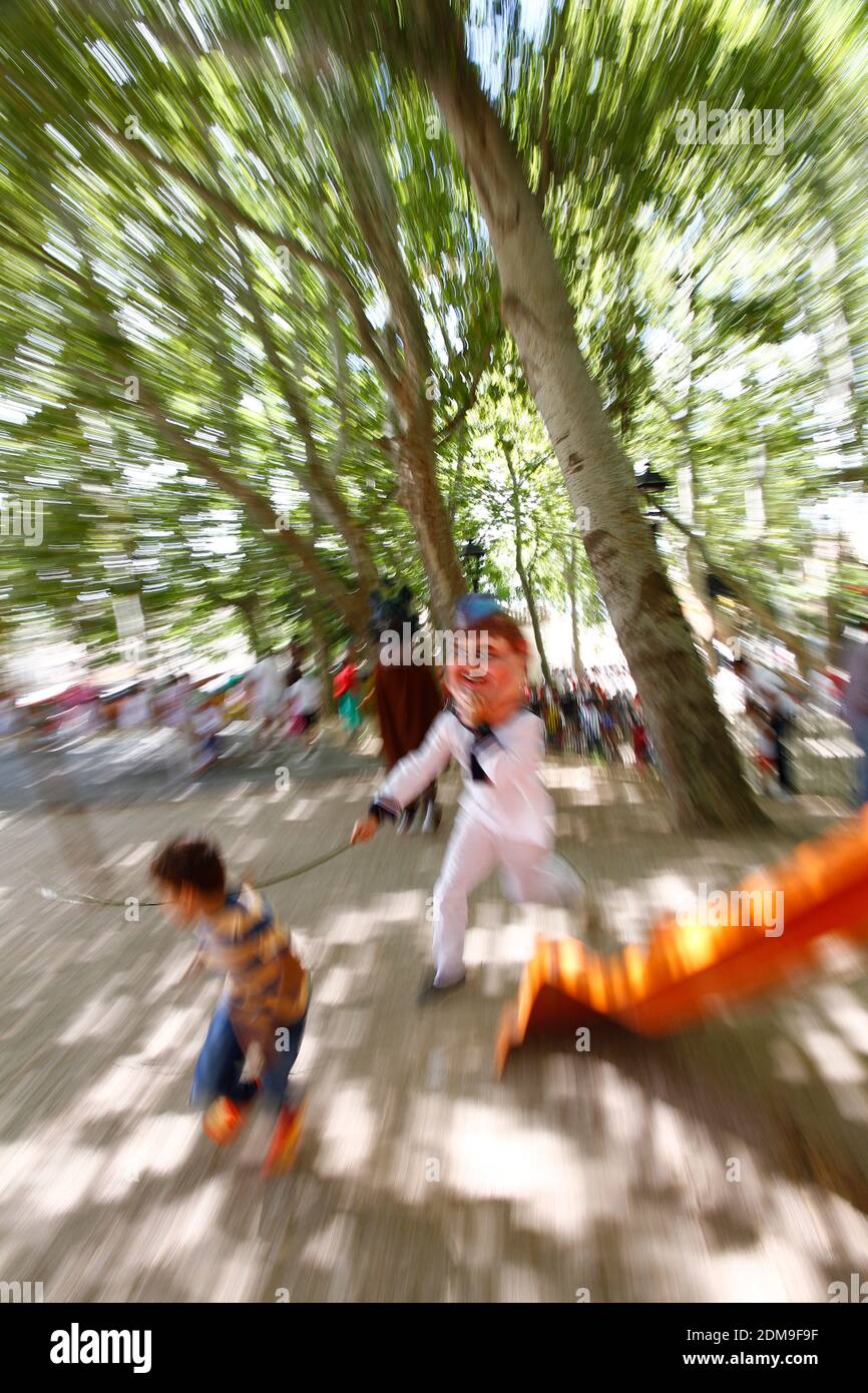 Giants and big-headed parade, a big-headed man with a stick in his hand chases a child who is trying to avoid the hit, zooming effect to emphasize dyn Stock Photo