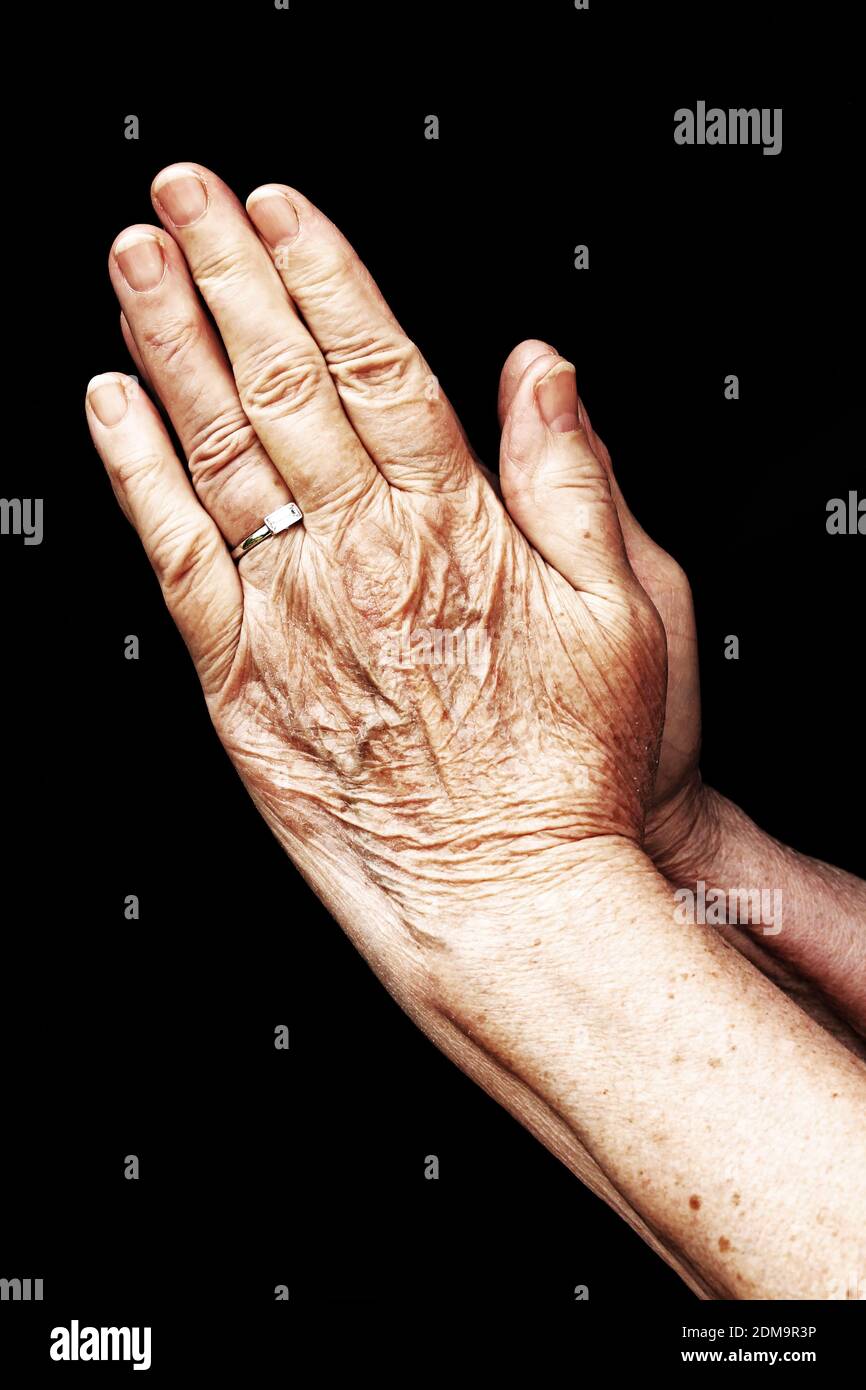 An old woman in prayer. Praying hands of an old woman Stock Photo