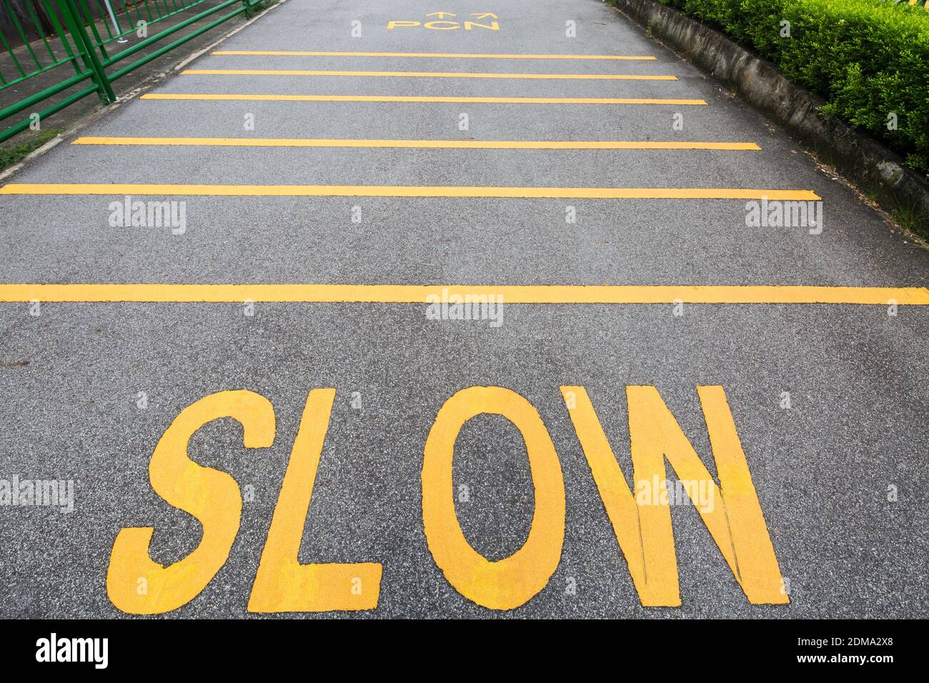 Slow sign and slow down yellow strips on the pavement at a public park