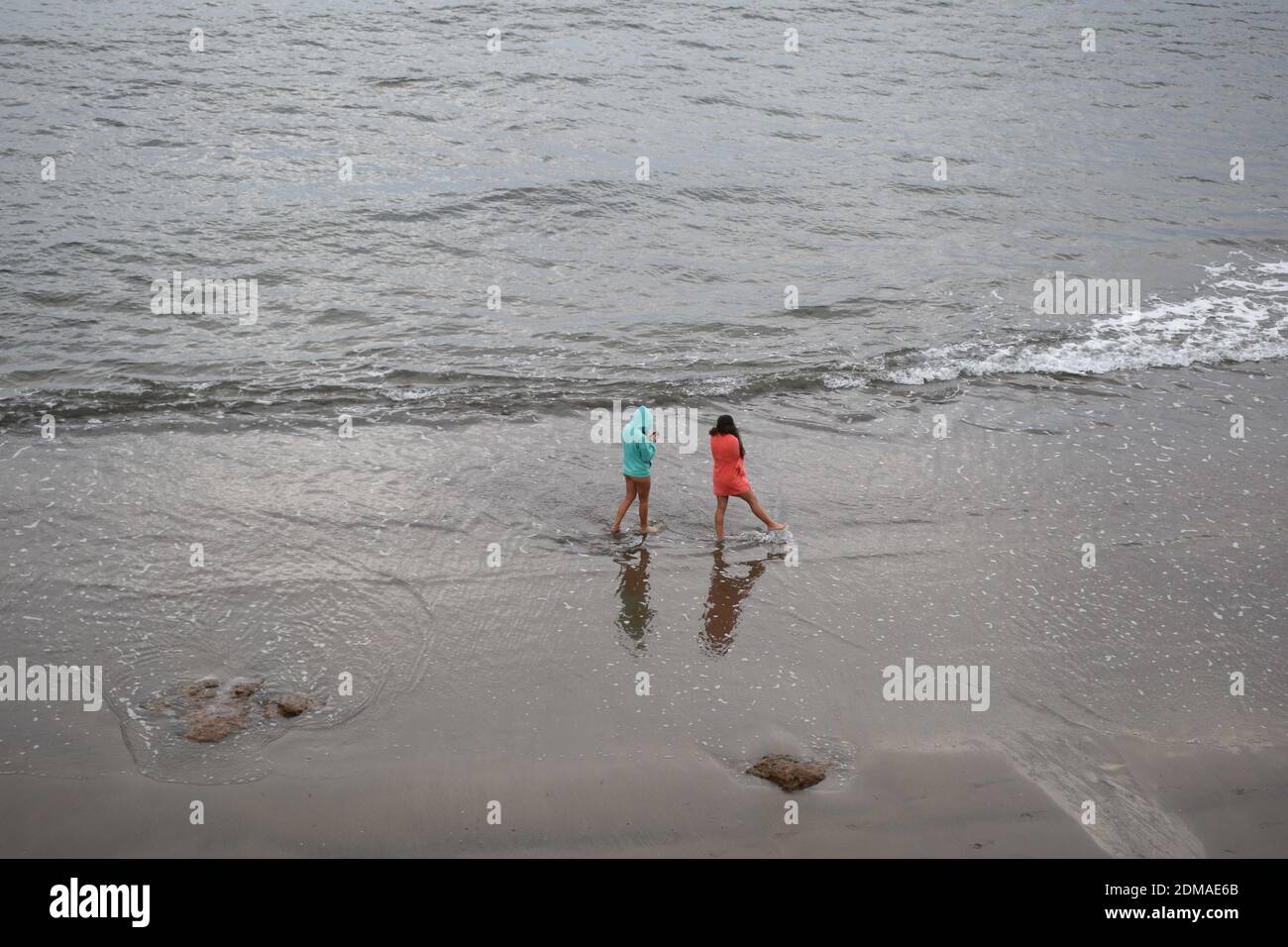 chicas en la playa de espalda paseando en la orilla del mas Cantabrico mojando los pies en las olas. Stock Photo