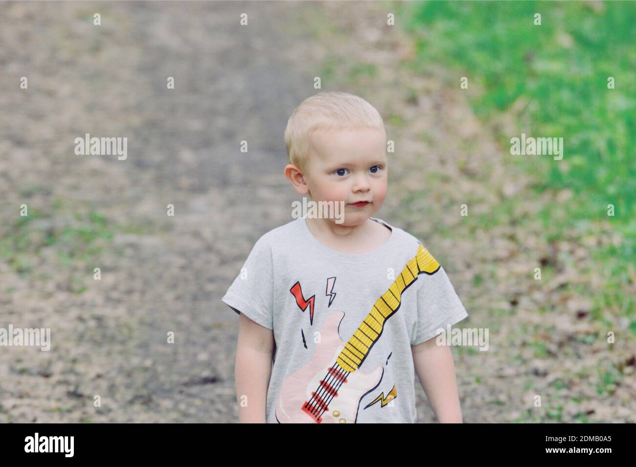 Cute Boy Looking Away Standing On Dirt Road Stock Photo