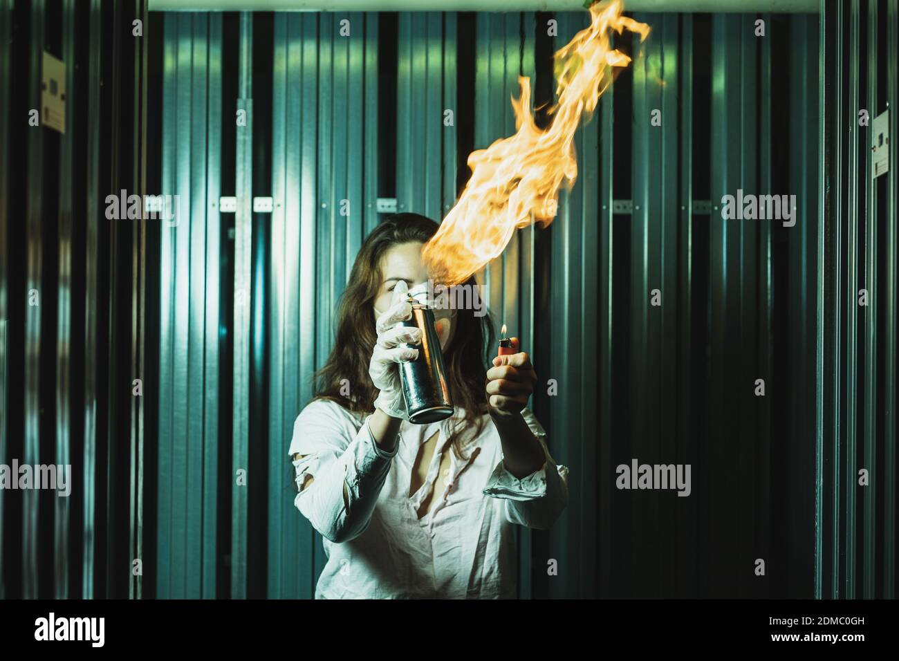 Woman Igniting Fire From Aerosol Can While Standing Against Metal Stock