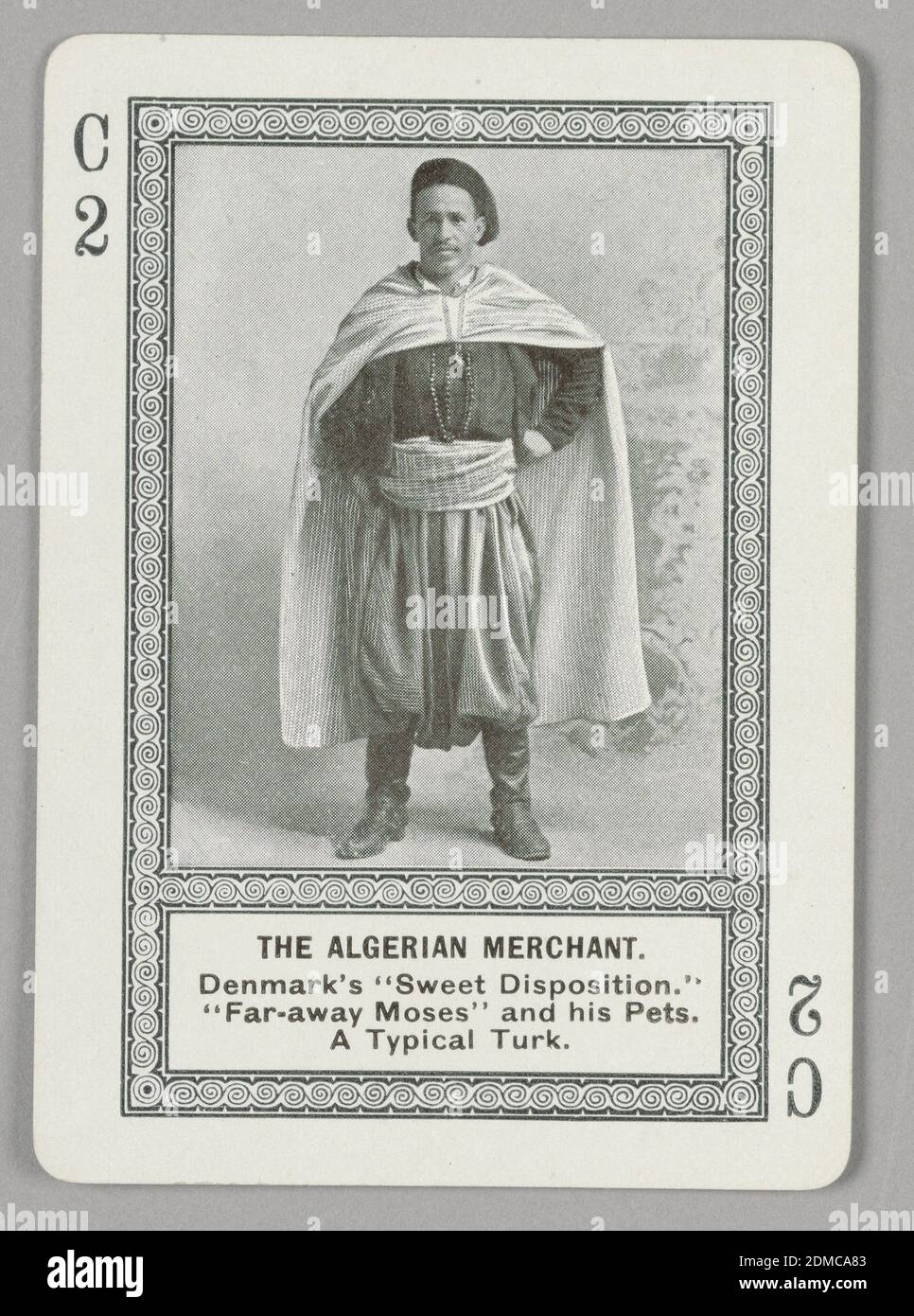 The Algerian Merchant, Game of Strange People, The Cincinnati Game Company, Cincinnati, Ohio, USA, Lithograph on paper, Rectangular format playing card with rounded edges, printed in black and white only. Part of a series of cards from an educational game featuring half-tone reproductions of people in national costumes from different countries around the world. Within rectangular swirling border, a photoillustration of a male figure in exotic non-Western costume, wearing boots, a hat, and a long cape. Below the image, printed in black ink: THE ALGERIAN MERCHANT. / Denmark's 'Sweet Disposition Stock Photo