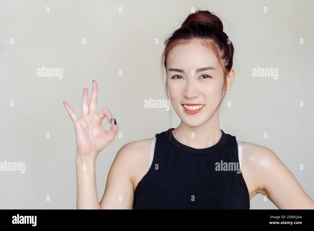 Portrait Of Smiling Young Woman Showing Ok Sign Against White Background Stock Photo