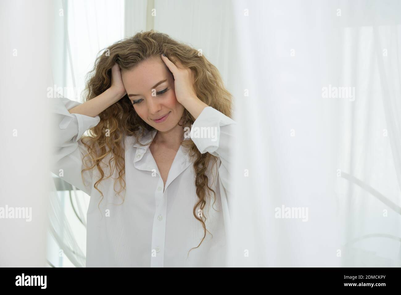 Beautiful smiling caucasian woman waking up and rubbing head on bed