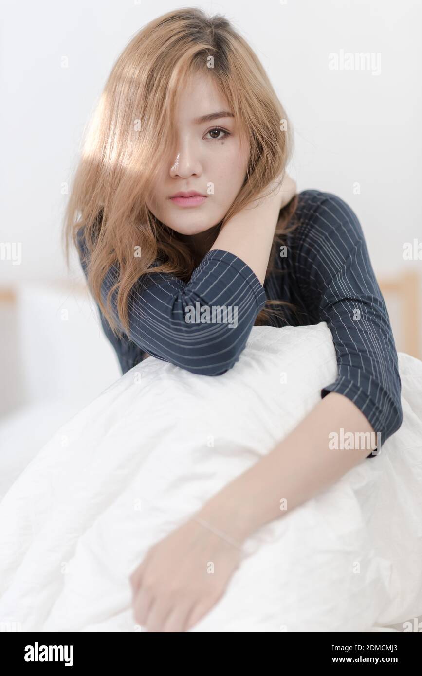 Portrait Of Young Woman Sitting On Bed At Home Stock Photo