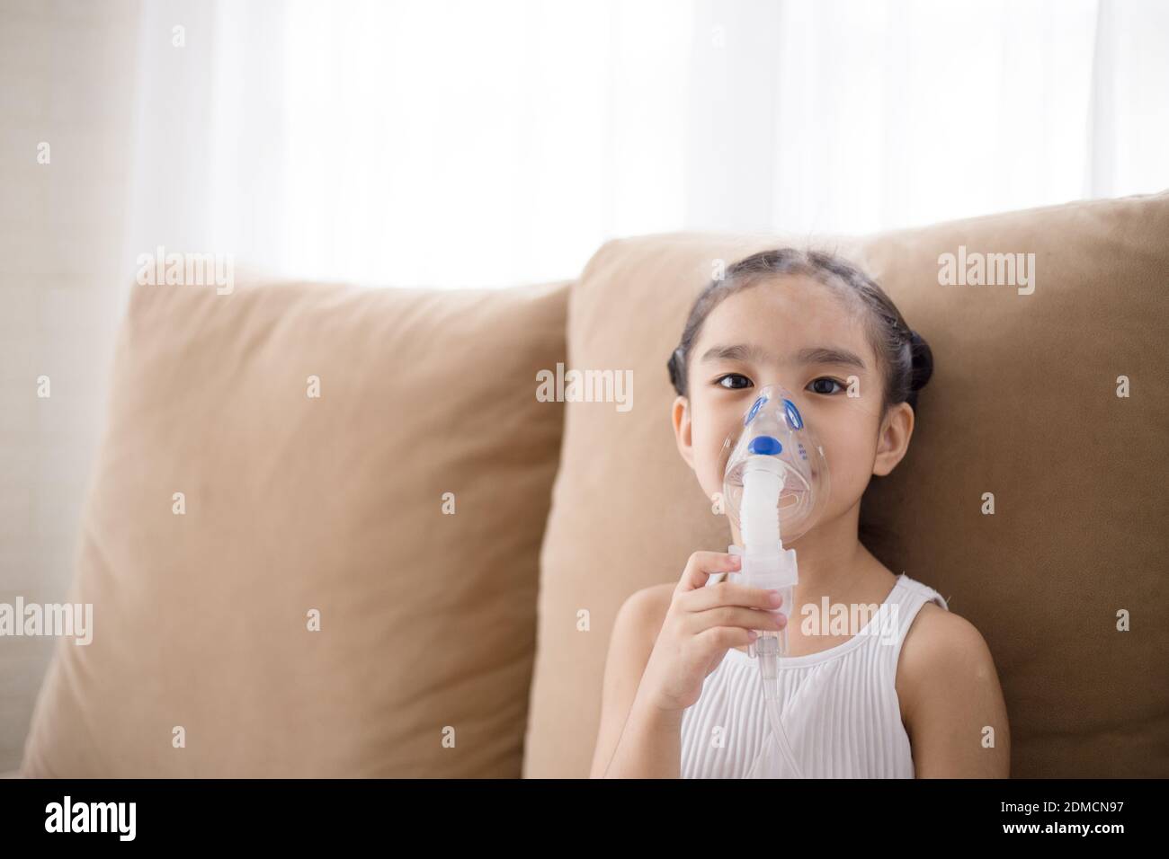 Cute Asian child patient inhalation therapy by the mask of inhaler with