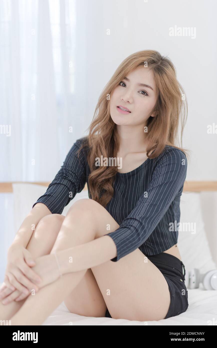 Portrait Of Young Woman Sitting On Bed At Home Stock Photo