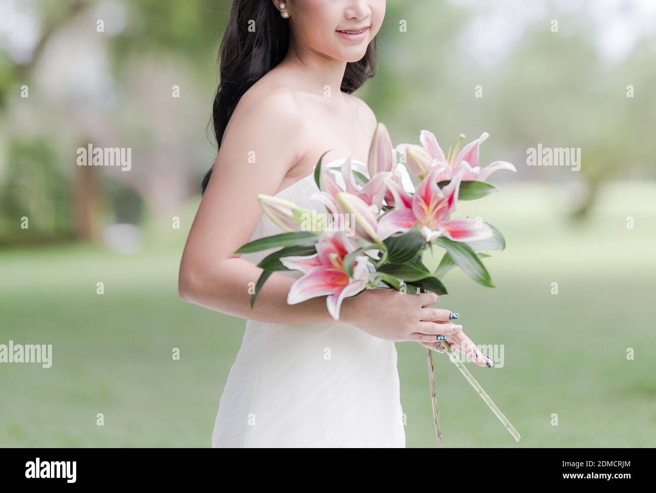 Midsection Of Smiling Bride Holding Flowers While Standing Outdoors Stock Photo